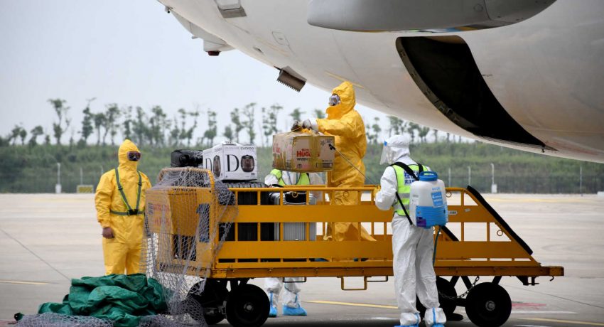 Workers in protective suits disinfect luggage arriving from South Korea at Wuhan Tianhe International Airport