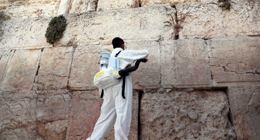 A labourer disinfects as he clears notes from Western Wall in Jerusalem's Old City
