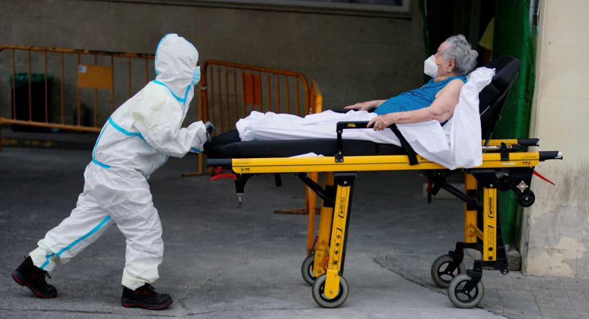 A healthcare worker wearing protective gear pushes a stretcher with a patient near the emergency unit of the 12 de Octubre hospital during the coronavirus disease (COVID-19) outbreak in Madrid
