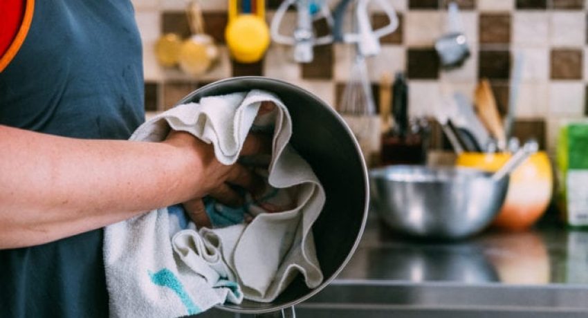 Close-Up from the side of a woman wiping the metal bowl with a kitchen towel in the kitchen