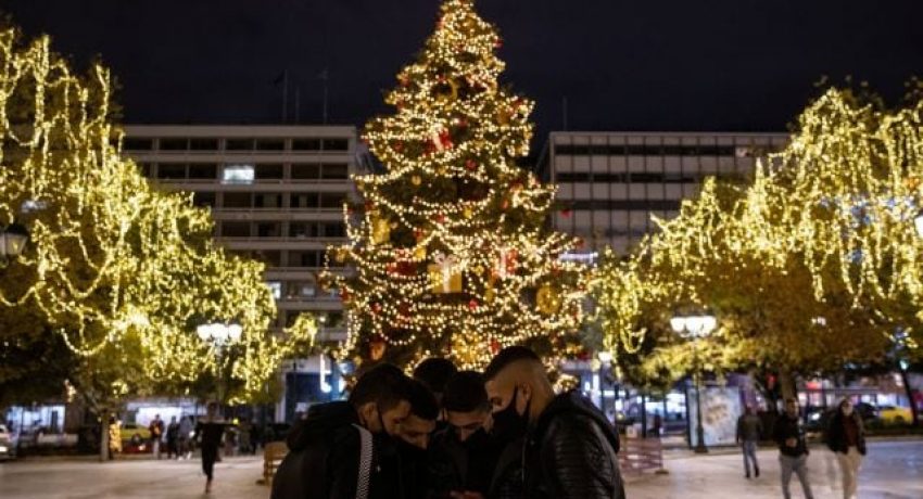 Youth wearing protective face masks look at a picture on a phone, as they stand in front of a Christmas tree on the illuminated Syntagma square, during the coronavirus disease (COVID-19) pandemic, in Athens, Greece, December 14, 2020. REUTERS/Alkis Konstantinidis