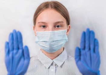 girl teenager 12-14 years old, in medical mask and gloves, focus on eyes, attention gesture of feet, carefully virus and flu virus and disease, stay home, stop pandemic of coronovirus covid 19