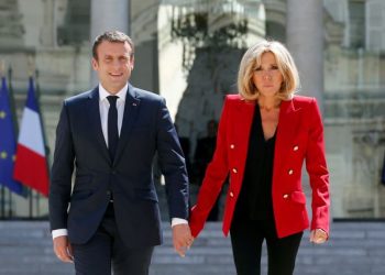 FILE PHOTO - French President Emmanuel Macron and his wife Brigitte Macron walk in the Elysee Palace courtyard July 6, 2017, to welcome guests, prior to the launching of a program to enhance the diagnosis and treatment of autism, in Paris, France.   Picture taken July 6, 2017.   REUTERS/Thibault Camus/Pool/File Photo