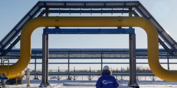 FILE PHOTO: An employee in branded jacket walks past a part of Gazprom's Power Of Siberia gas pipeline at the Atamanskaya compressor station outside the far eastern town of Svobodny, in Amur region, Russia November 29, 2019.  REUTERS/Maxim Shemetov./File Photo