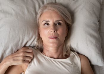 Middle aged mature woman insomniac lying awake in bed looking up trying to sleep, unhappy old senior lady feel disturbed frustrated suffer from insomnia concept uncomfortable bad mattress, top view