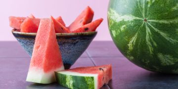Whole watermelon and slices in ceramic bowl with copy space. Shallow depth of field.